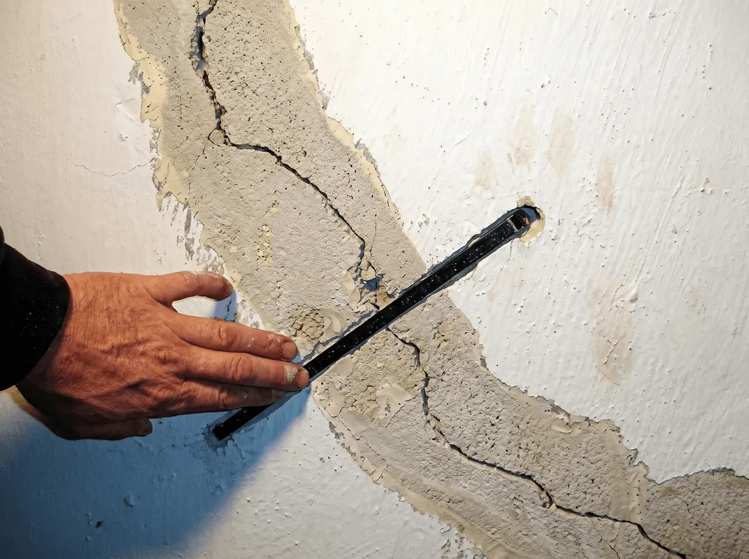 A wall with a large crack is being inspected by a professional in Wilmington, NC